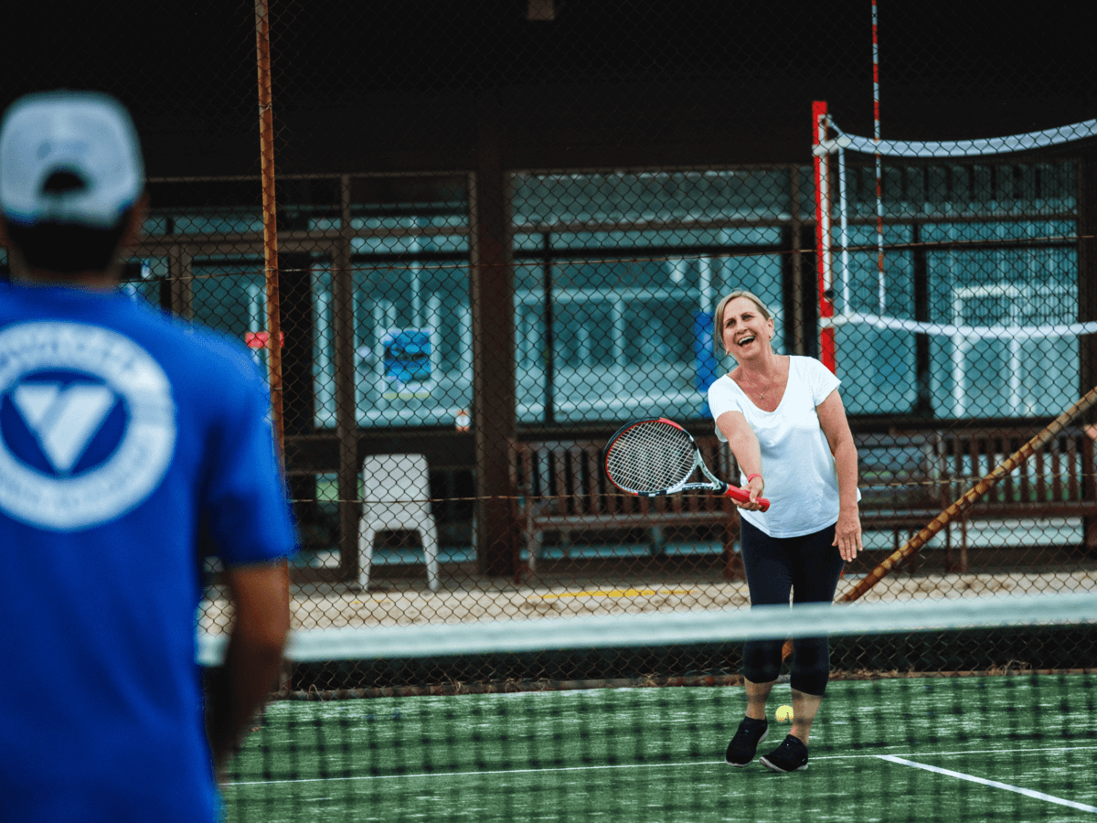 A Voyager coach guiding an adult player playing tennis