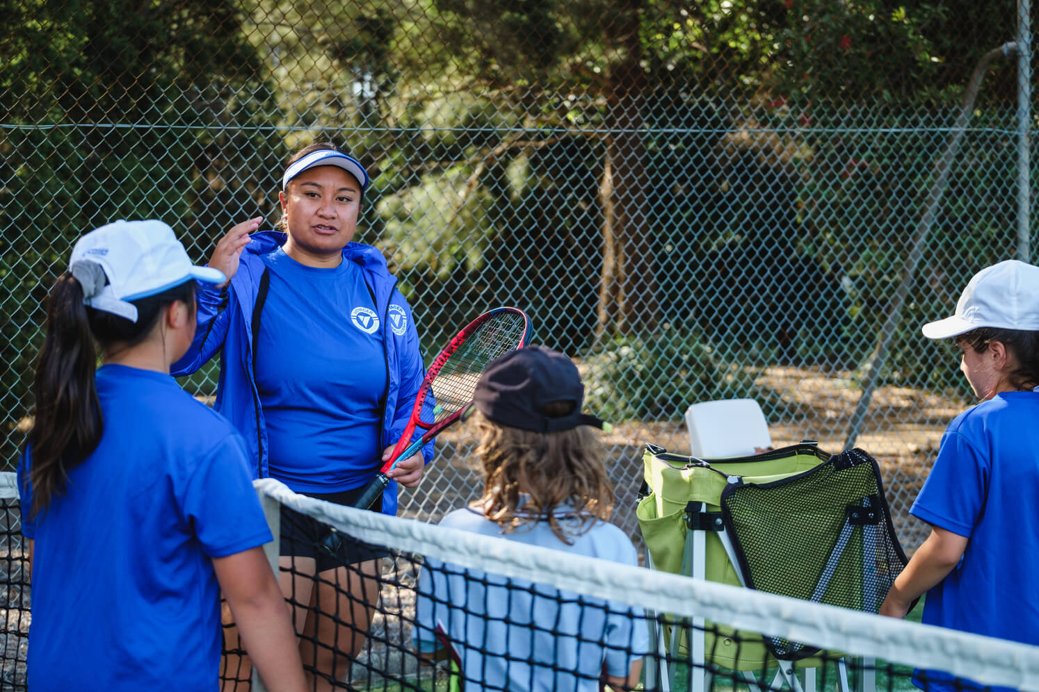 The coach discusses proper tennis drills to the kids